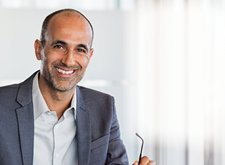 Man sitting in an office holding glasses
